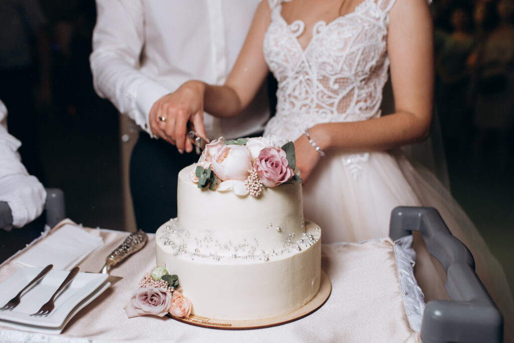 Bride and groom are cutting decorated with flowers wedding cake