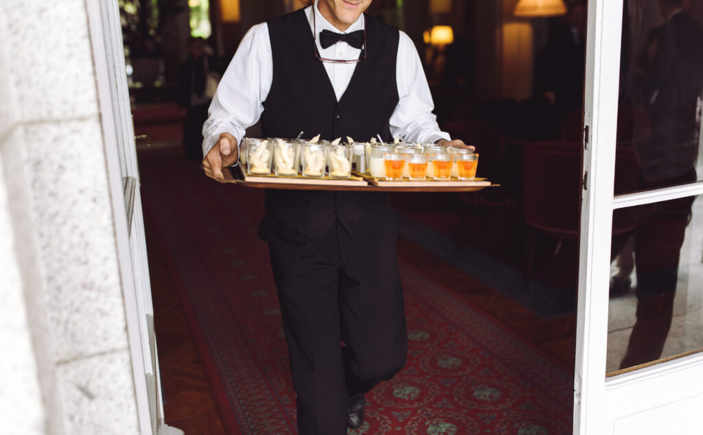 Waiter carries dish with snacks walking to the backyard